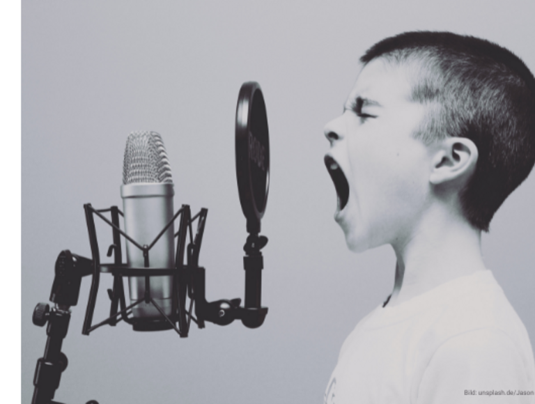 Ein Kind ruft etwas in ein Mikrofon.